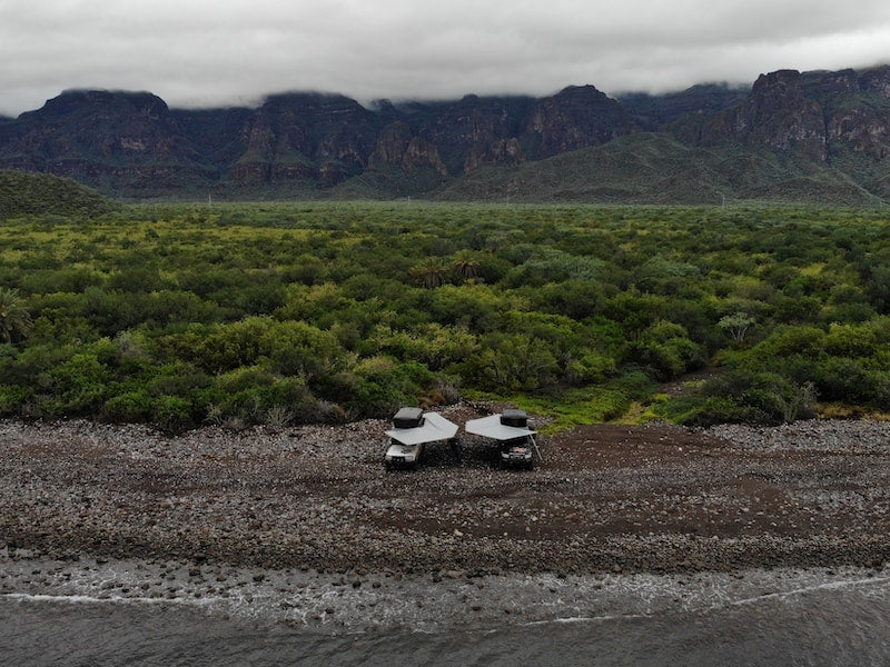 Aerial view of two overland vehicles posted up at beach with RLD GhostAwn 360 awnings